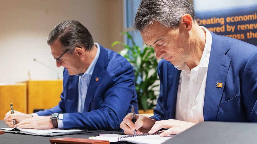 Sun Cable CEO David Griffin signs a development agreement with Northern Territory Chief Minister Michael Gunner. They smile.