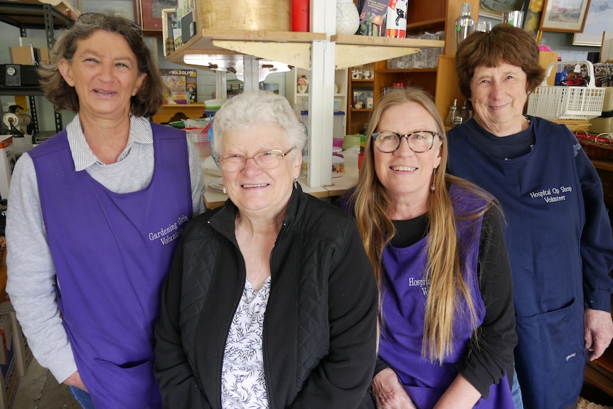 Four women, some wearing purple volunteer vests