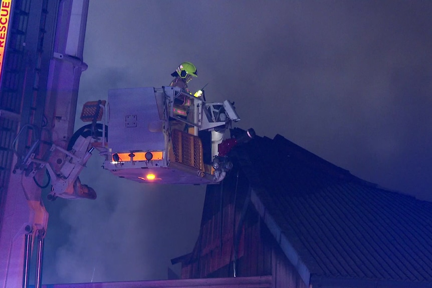 fire fighter in smithfield stands on raised scissor lift inspecting fire damage