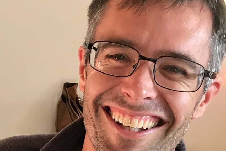 Man with short hair and glasses smiling