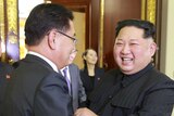 Kim Jong-un smiles as he shakes hands with a South Korean official.