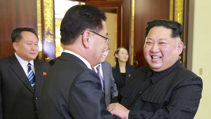 Kim Jong-un smiles as he shakes hands with a South Korean official.