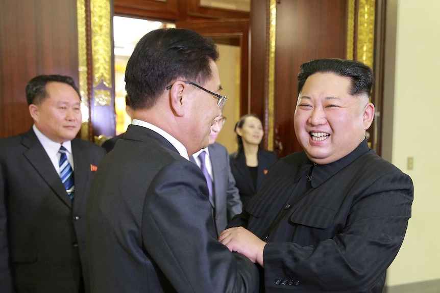 Kim Jong-un smiles as he shakes hands with a South Korean official.