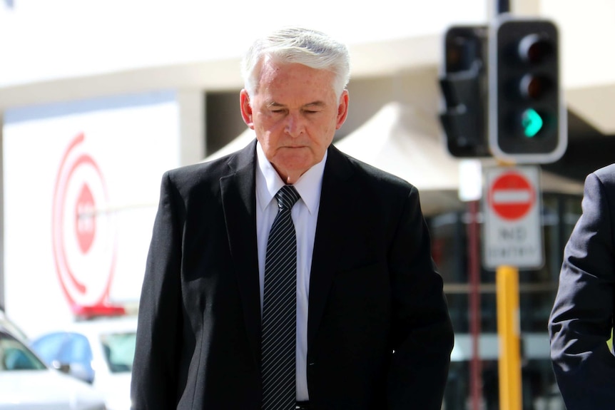 Catholic Bishop Max Davis crosses the road wearing a suit.