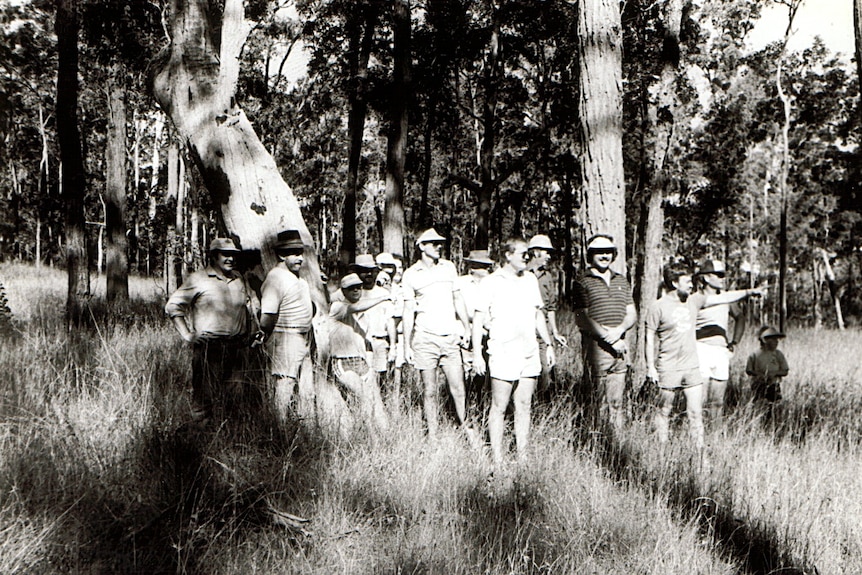 A black and white photo of a group of people in the bush.