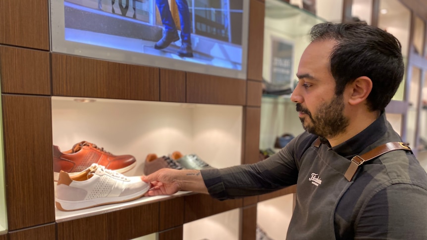 Florsheim store manager Gabriel Selim stocks shelves with shoes.