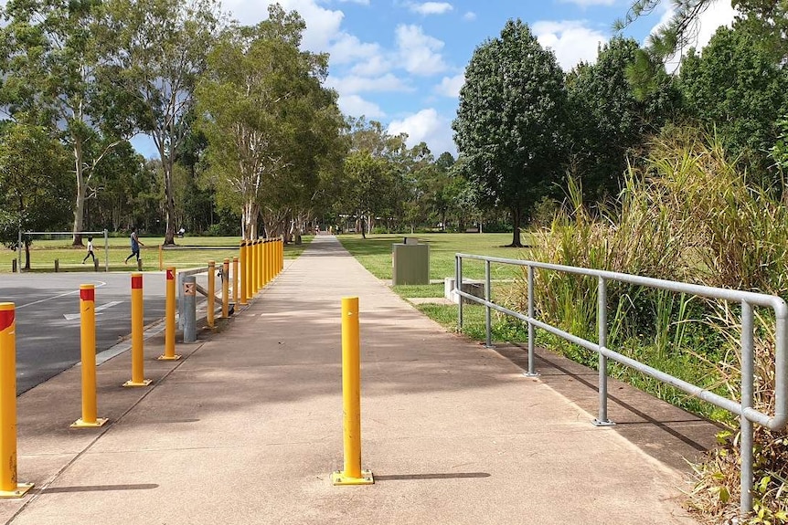 Pathway with park in the distance and road to the left.