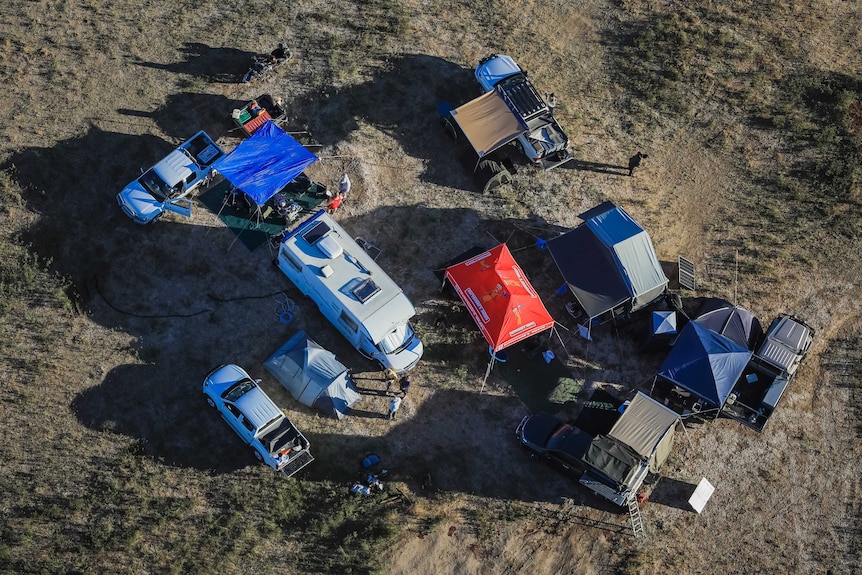 Aerial view of tents and campervans on the grass.