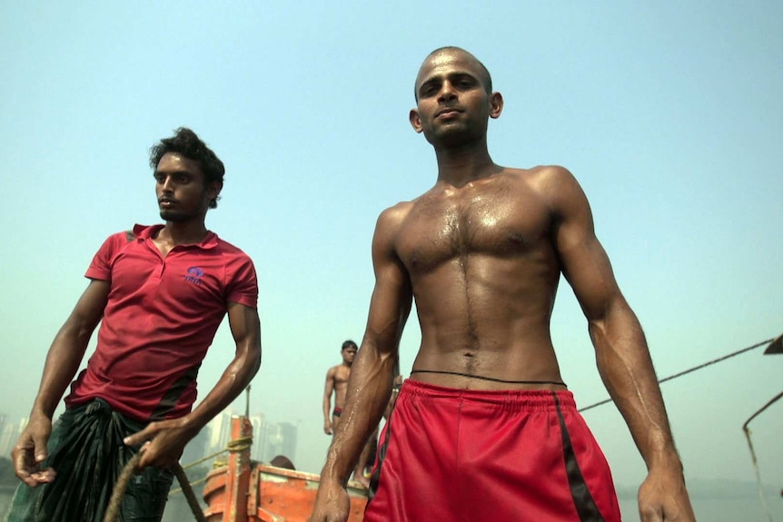 Two Indian men, one bare-chested, look at the camera