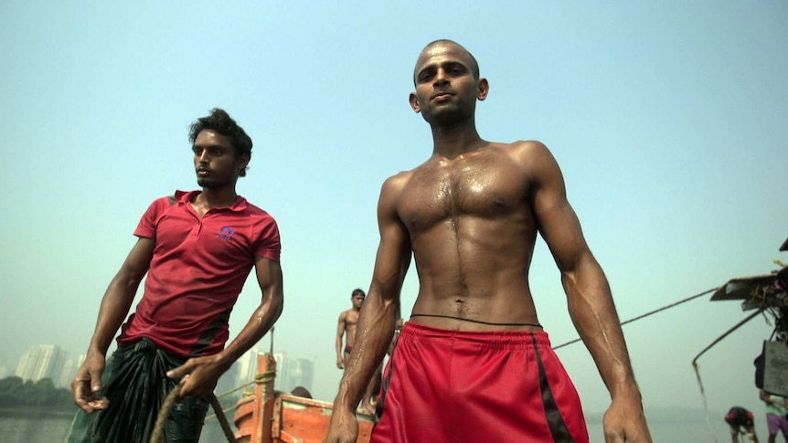 Two Indian men, one bare-chested, look at the camera
