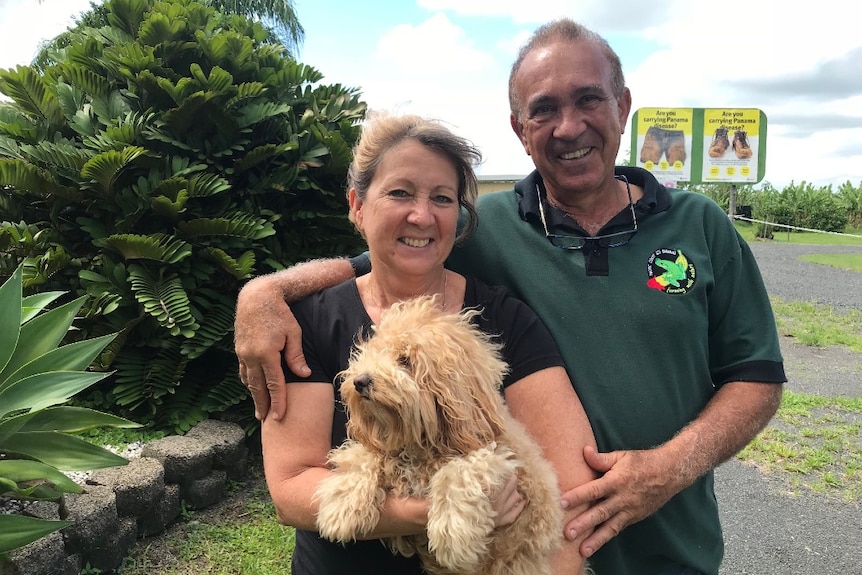 Frank and Dianne look into the camera, smiling, and holding a small fluffy dog.