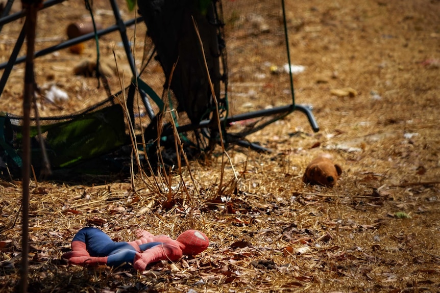 A Spiderman doll lays in the backyard of a home where police have established a crime scene.
