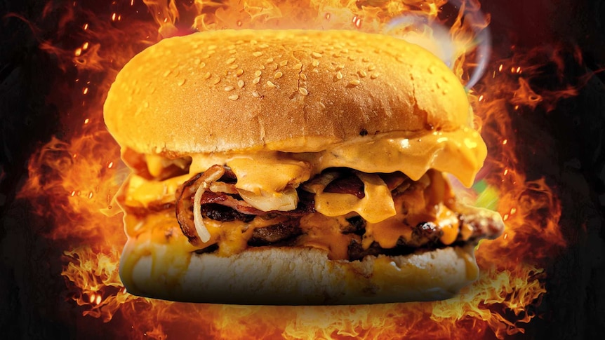 A big juicy burger with flames in the background.
