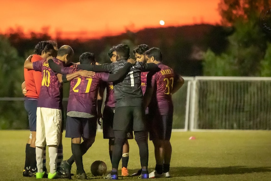 A huddle of men on a soccer field