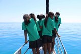 Girls from  the Broome Senior High School are standing on the bow of a sailing boat, looking for whales.