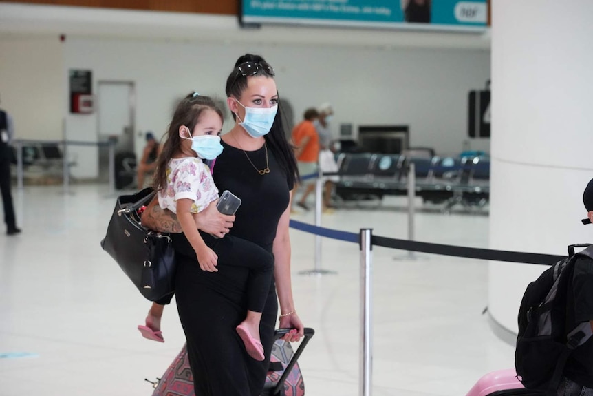 A woman and a child wearing masks, arrive at Perth Airport.