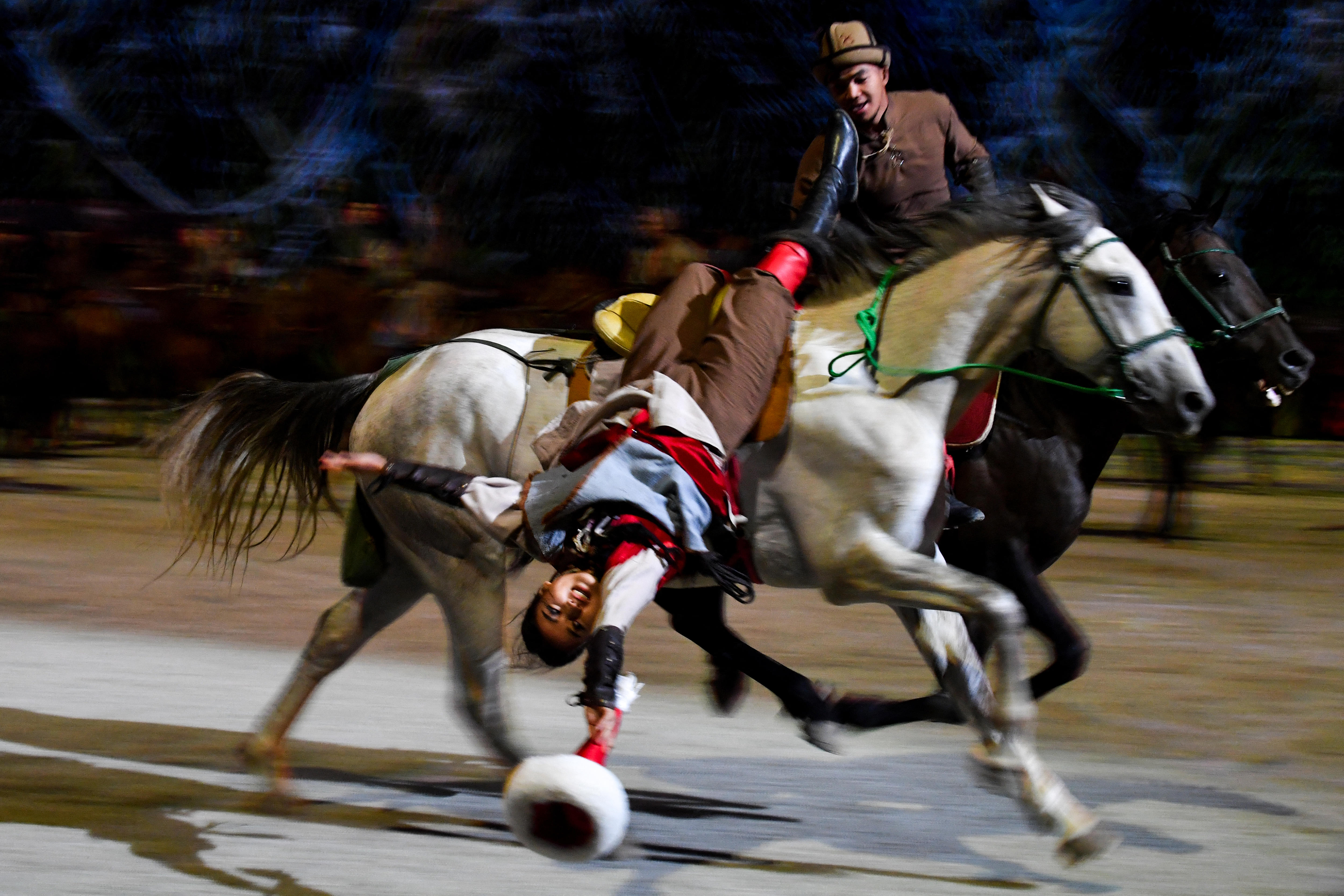woman hangs upside down from a galloping horse.