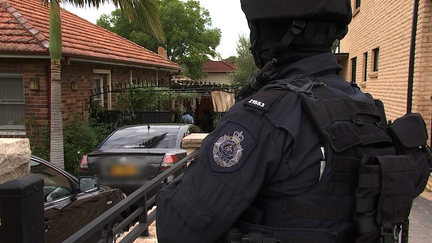 A police officer looking at a house.