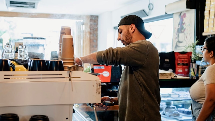 Man makes a coffee at a machine in a cafe.