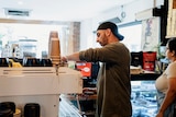 Man makes a coffee at a machine in a cafe.