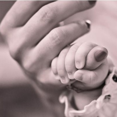 Black and white photo of an adult's hand holding a baby's hand 