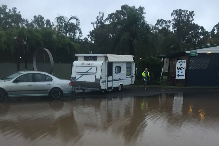 A car with a caravan is parked nearby flooding.