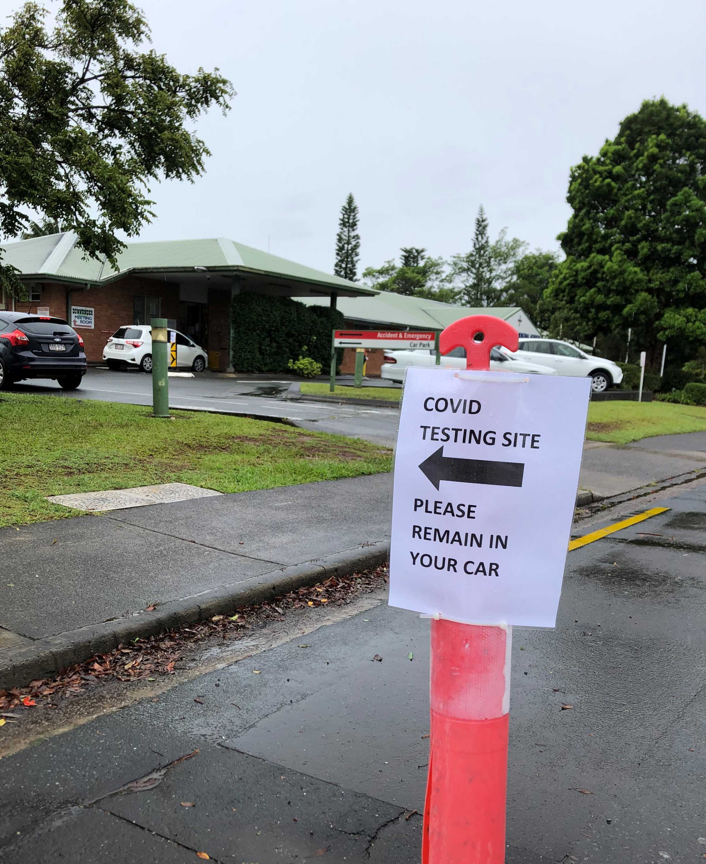 Sign saying 'covid testing site please remain in your car' attached to bollard at Maleny Soldiers Memorial Hospital