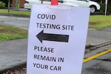 Sign saying 'covid testing site please remain in your car' attached to bollard at Maleny Soldiers Memorial Hospital
