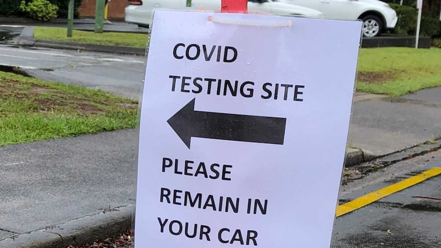 Sign saying 'covid testing site please remain in your car' attached to bollard at Maleny Soldiers Memorial Hospital