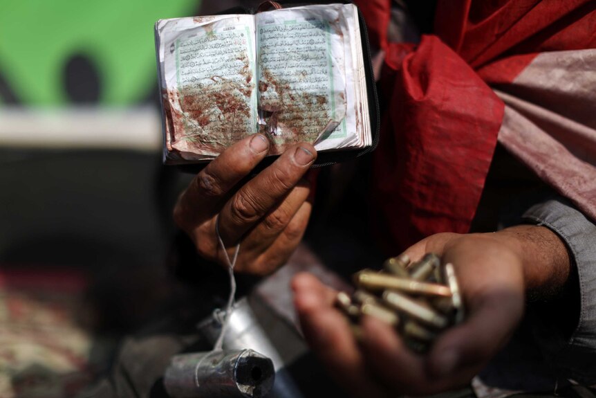 Morsi supporter holds bullets and bloodied Koran
