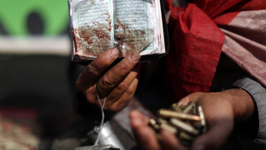 Morsi supporter holds bullets and bloodied Koran