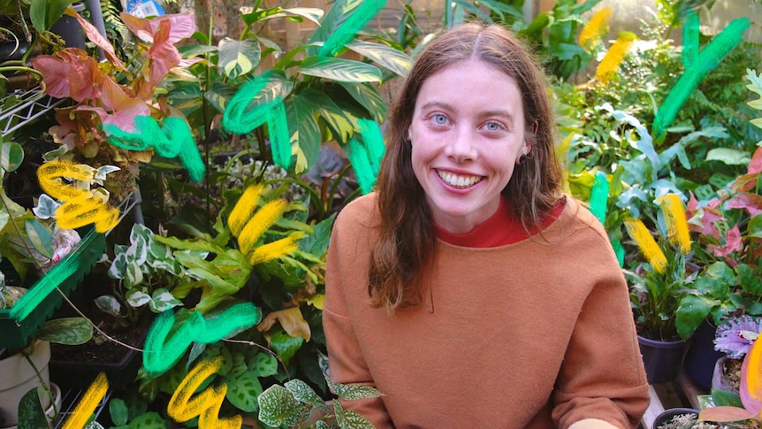 Woman wearing a brown jumper kneeling in front of many pot plants