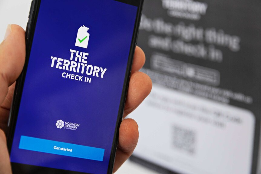 Fingers tient un téléphone mobile qui affiche un écran bleu avec des mots blancs indiquant The Territory Check In.
