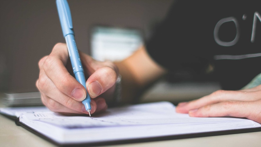 A person writing with a blue pen.