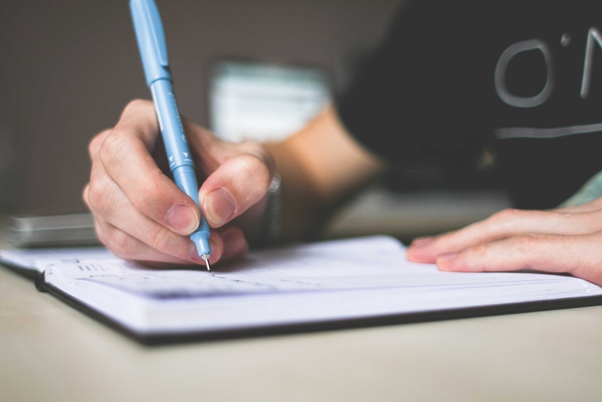 A person writing with a blue pen.