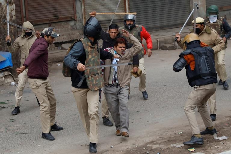 Police officers detain a demonstrator during a protest.