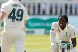 England bowler Jofra Archer squats and looks at Australia batsman Steve Smith, seen from behind, during an Ashes Test match.