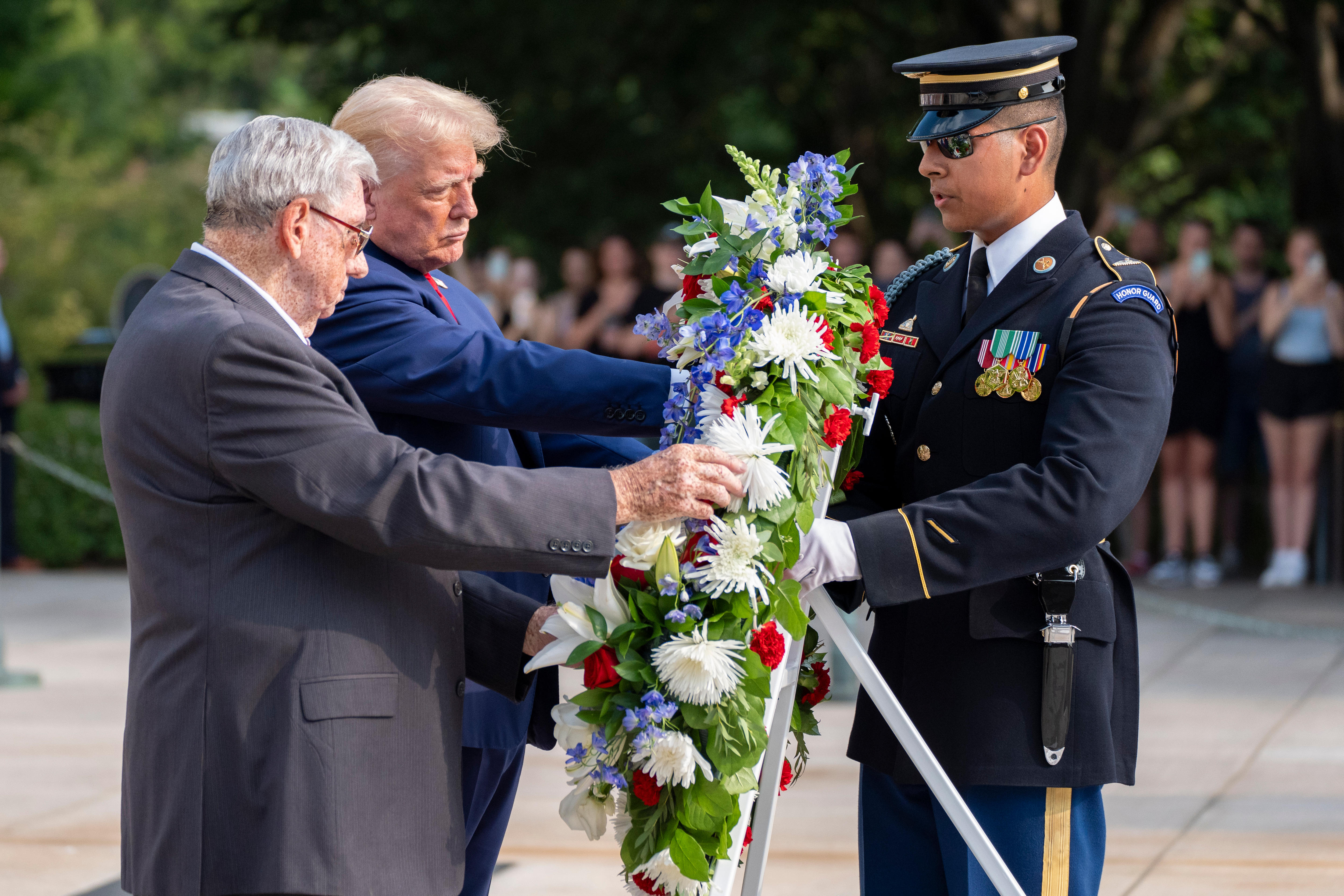 US Army official holds wreath alongside Donald Trump and elderly man