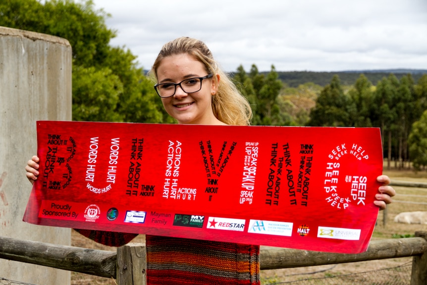 Girl holding red poster covered in words