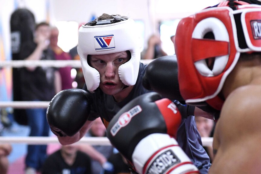Jeff Horn (left) in head gear with boxing glove covered fists propped beneath his chin