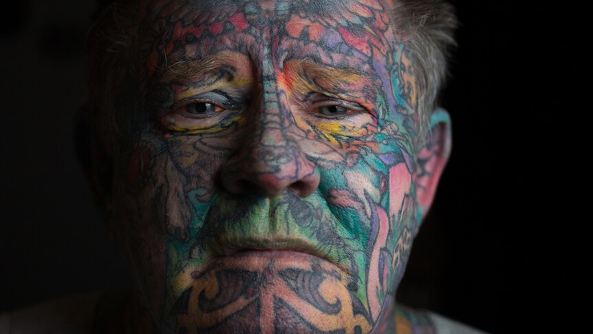 Close-up portrait of John Kenney's tattooed face