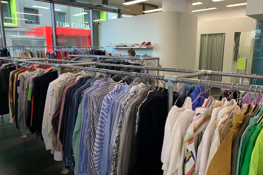 a clothing store with racks of clothes and shoppers