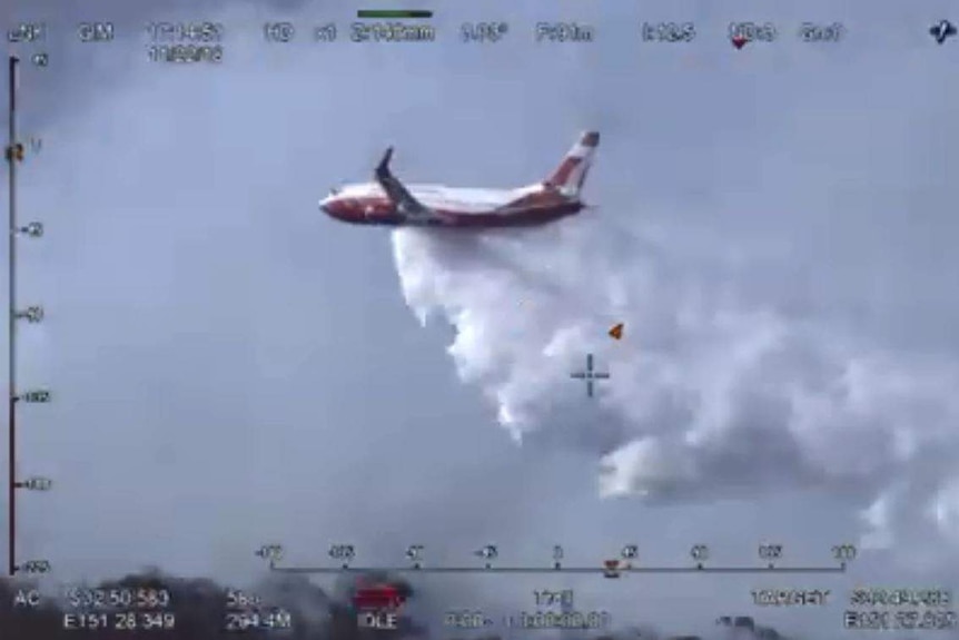 An aircraft drops water on a bushfire