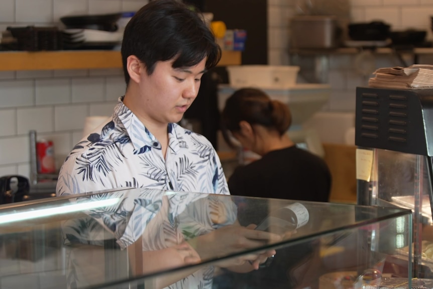 A man working behind the counter in a sushi shop.