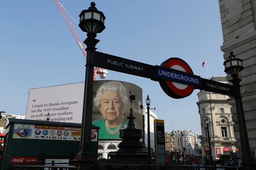 The Queen's face appears on a billboard in Piccadilly Circus.