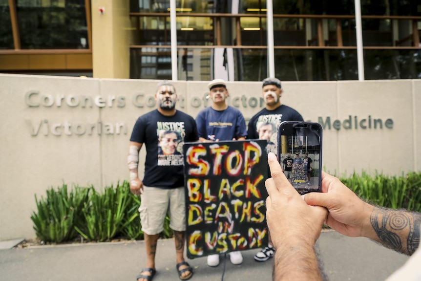 Supporters hold a placard that reads stop black deaths in custody