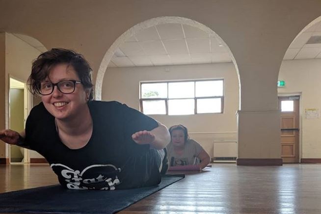 A woman with short dark hair and glasses exercises on a yoga mat. For story on women finding exercise that suits them.