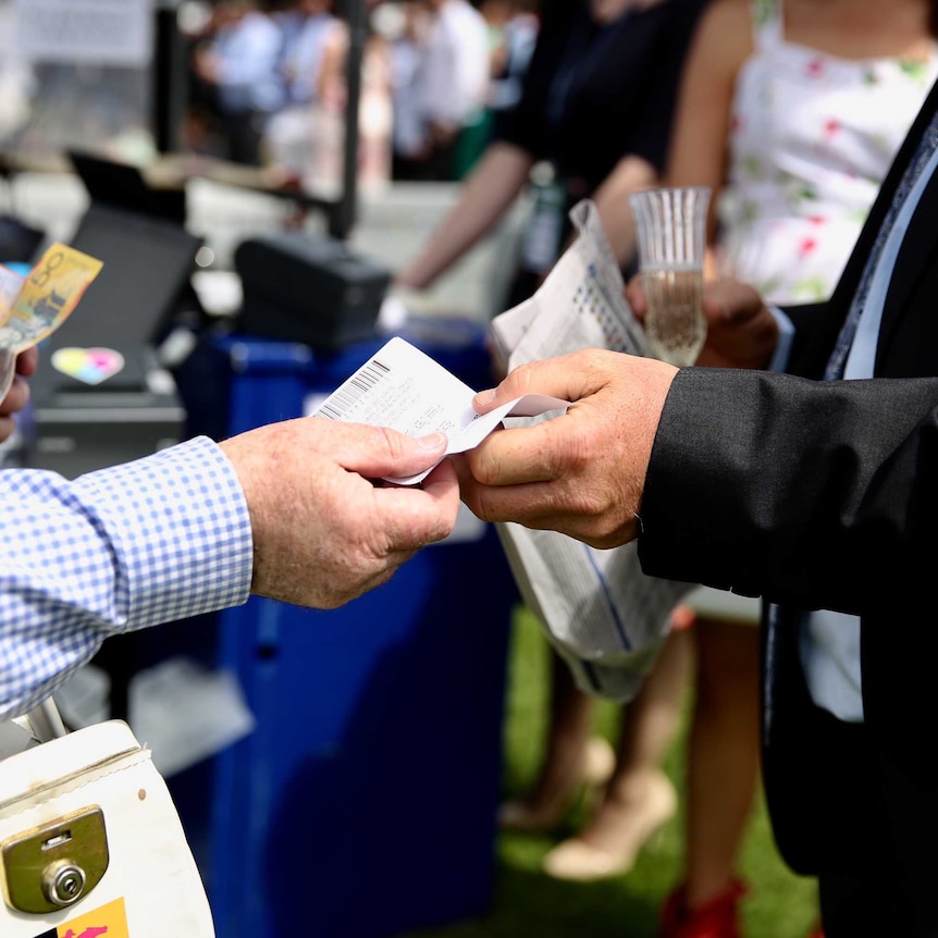 Someone places a bet and hands over cash at the Melbourne Cup.
