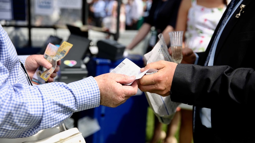 Someone places a bet and hands over cash at the Melbourne Cup.