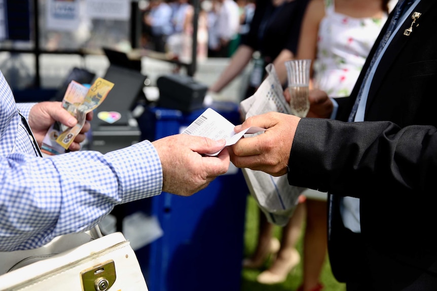 Someone places a bet and hands over cash at the Melbourne Cup.